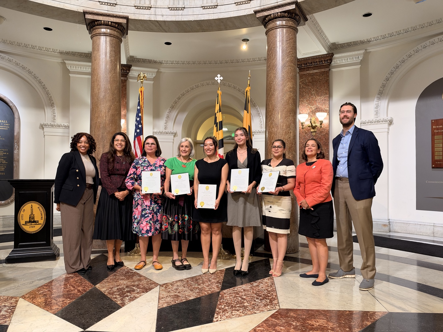 Award recipients and guests holding certificates at Baltimore City Hall.